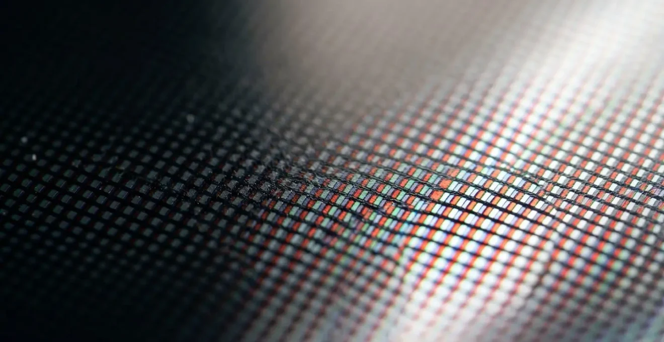 Close-up view of a modern 4K television displaying technical signal patterns with shallow depth of field, emphasizing premium display panel texture and color fidelity
