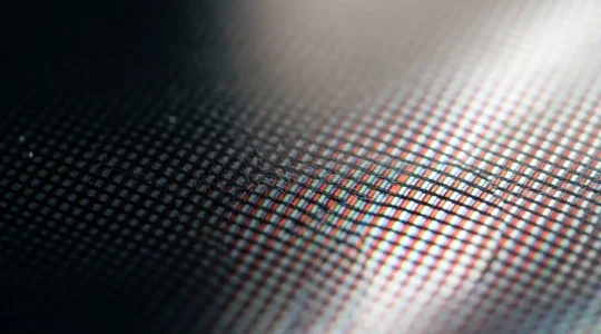 Close-up view of a modern 4K television displaying technical signal patterns with shallow depth of field, emphasizing premium display panel texture and color fidelity